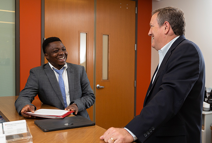 Two professional individuals talking and smiling in a large room