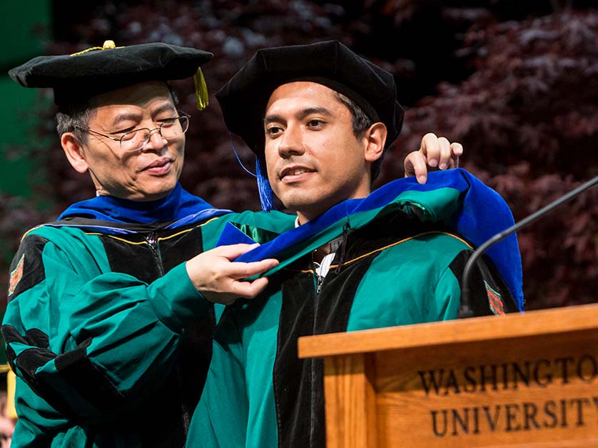 An Olin faculty member hooding a PhD graduate at graduation.