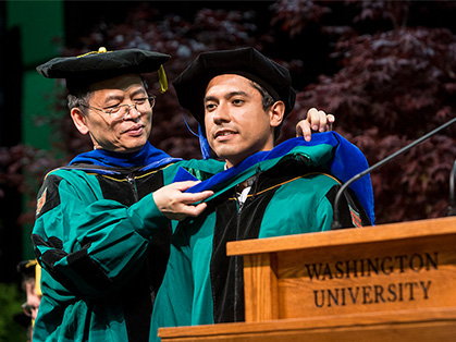 An Olin faculty member hooding a PhD graduate at graduation.