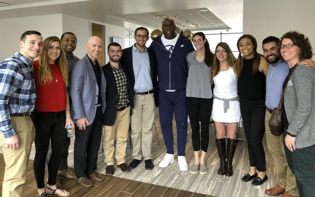 Earvin “Magic” Johnson, Los Angeles Lakers point guard for 13 seasons, stands with WashU students and staff at the Lakers practice facility in El Segundo, CA, on Monday, March 12, 2018. Said Rishe: “This was totally unexpected, and Magic couldn’t have been any nicer or more gracious.” Visitors with Magic include Michael Weisman, Taylor Cohen, Bryant Powell, Rishe, Issac Kaufer, Allan Bekerman, Magic Johnson, Kelly Minster, Teresa Iadevito, Katie Sissler, Oscar Vasco, and Konnie Henning.
