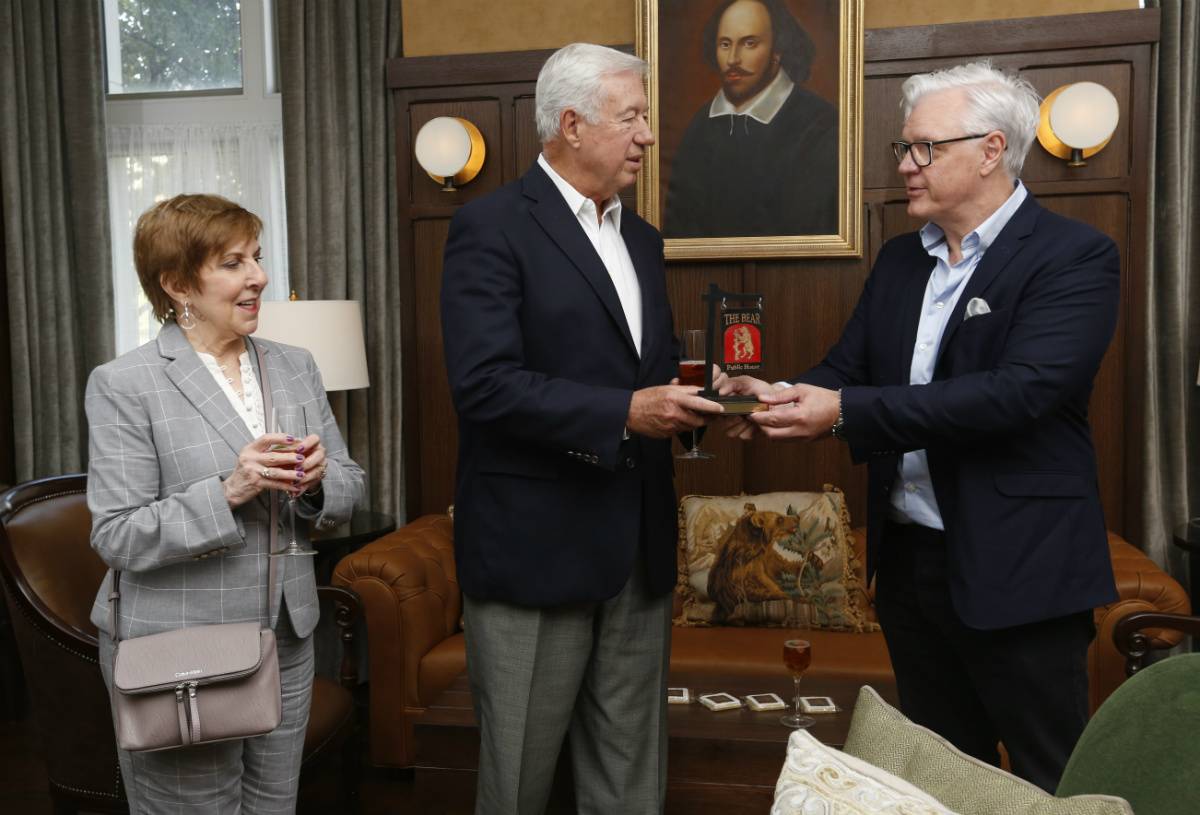 Dean Mark P. Taylor, right, offers a token of appreciation—a miniature Bear pub sign—to Bob and Kathleen O’Loughlin, benefactors of the new space.