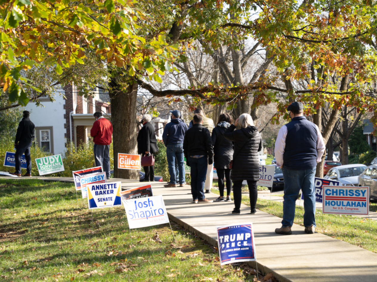 People lining up outside of an election polling place to vote.