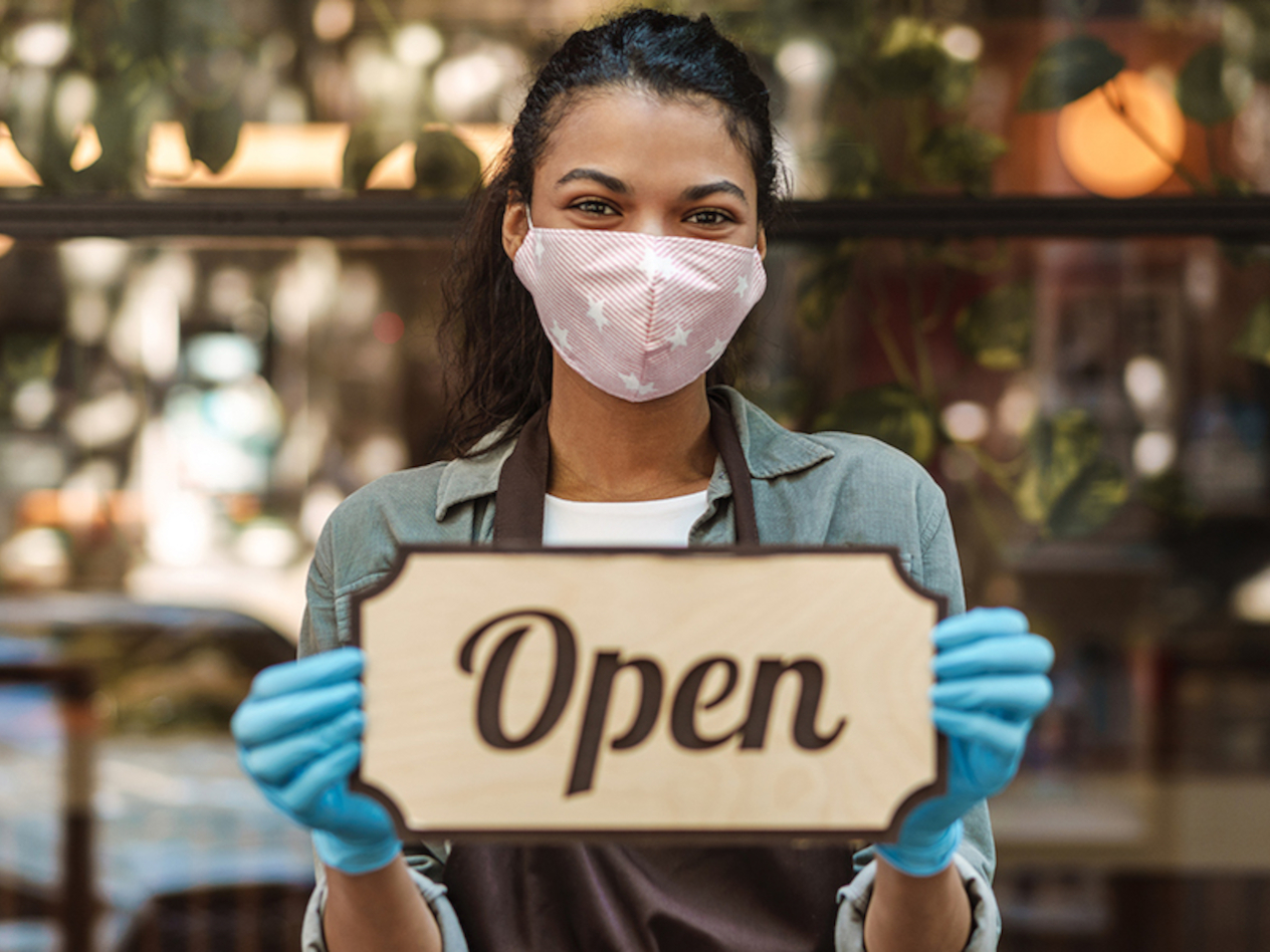 Woman coffee shop owner with face mask opens after lockdown quarantine