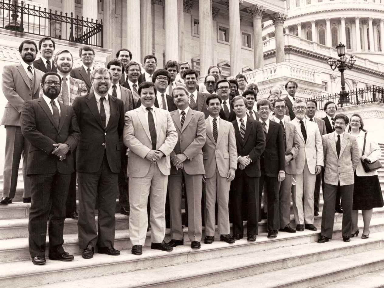 1984-era black-and-white group shot of the first EMBA class standing on the steps of the US Capitol building.
