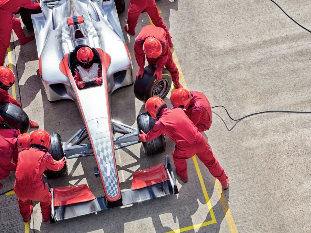 Photo shot from above, looking down at a Formula 1 pit crew working on a car.