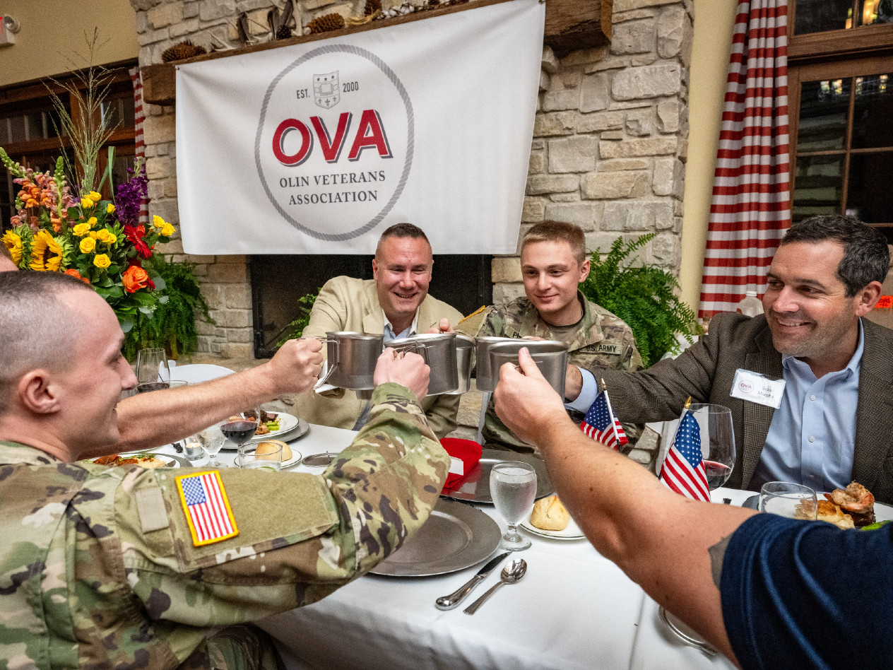 military veterans share a toast holding metal canteen cups