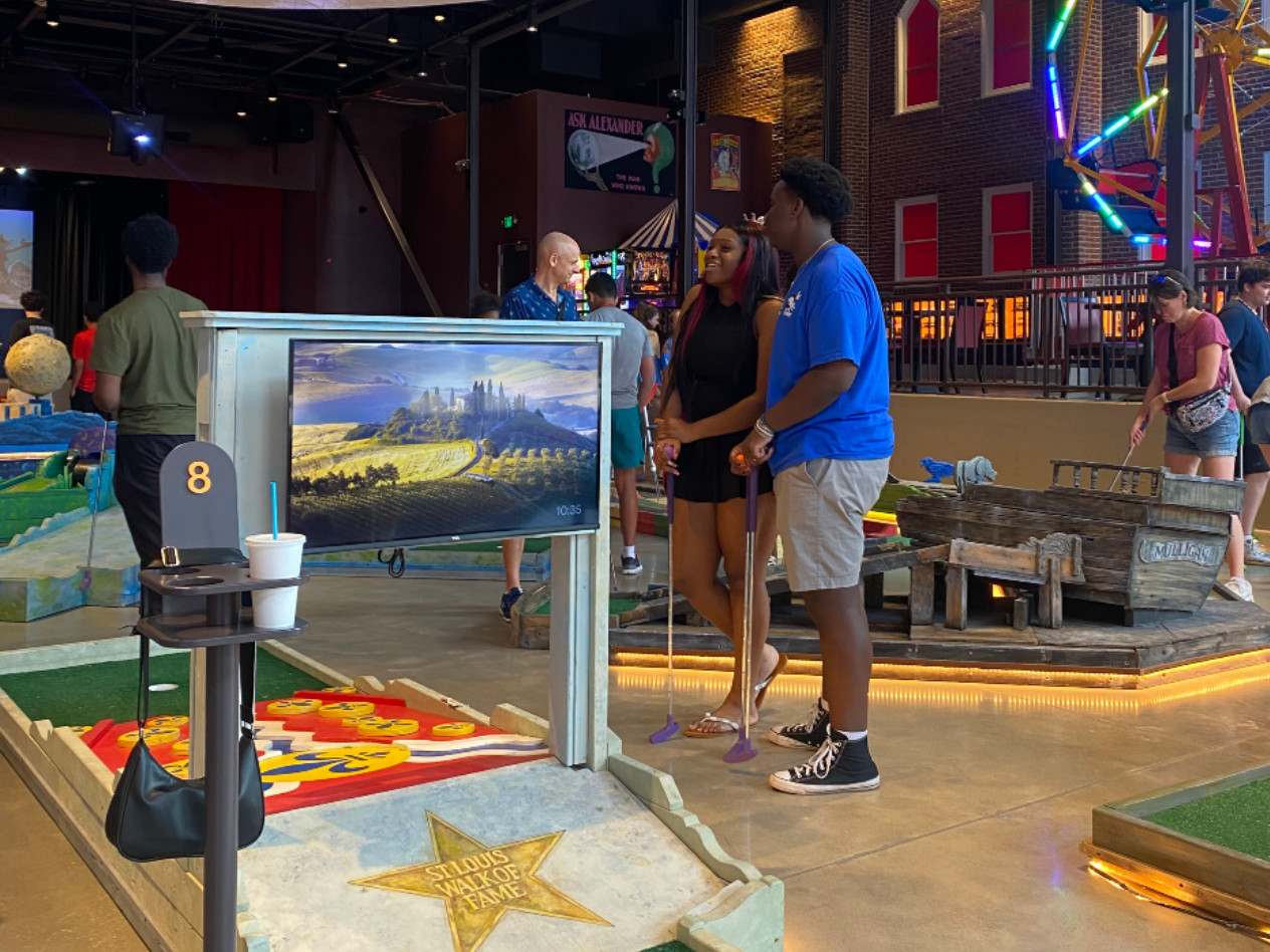 Students playing mini golf at an indoor course