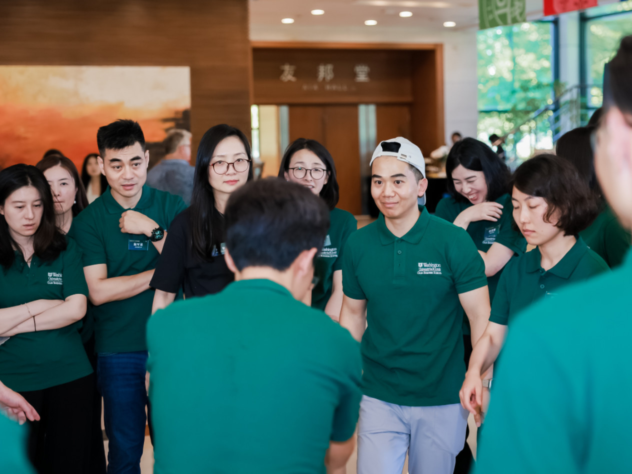 A group of students in green shirts talking to one another.